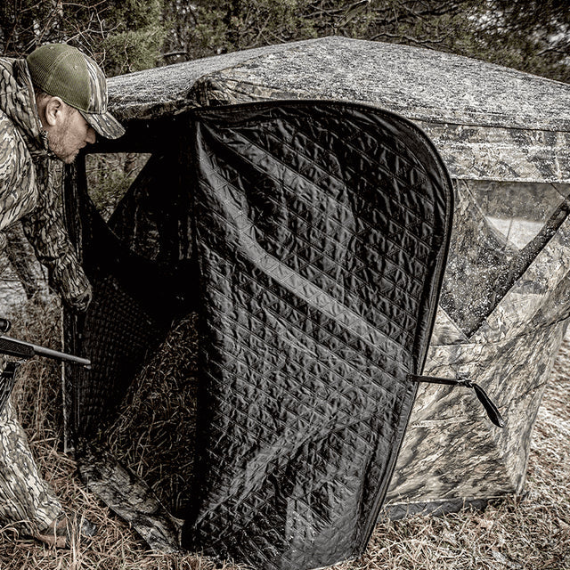 Ameristep Pro Series Insulated 59x59 pop-up ground blind with hunter in camouflage gear entering through zippered door in a wooded field