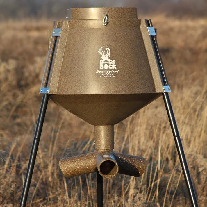 Boss Buck 200 lb Gravity Deer Feeder in open field — compact brown feeder with three steel legs and 3-way gravity head for consistent wildlife feed flow.