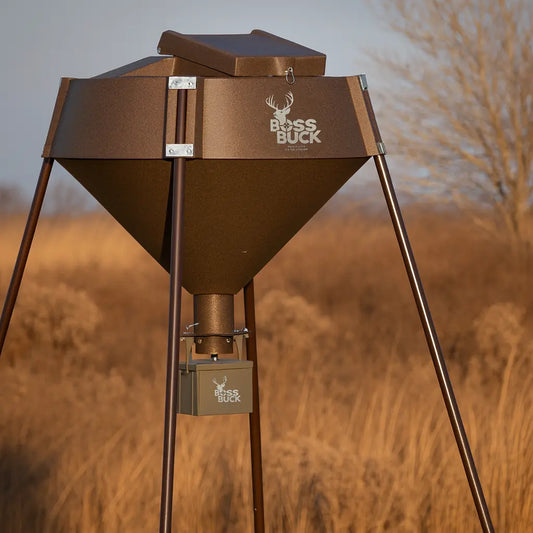 Boss Buck 600 lb Automatic Deer Feeder set up in field — brown rotomolded hopper on tripod stand with 12-volt timer and spinner system for consistent deer feeding.