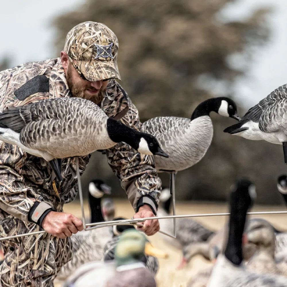 Avian-X X-Stand for Decoys in use by camo-clad hunter setting up Canada goose decoys in the field