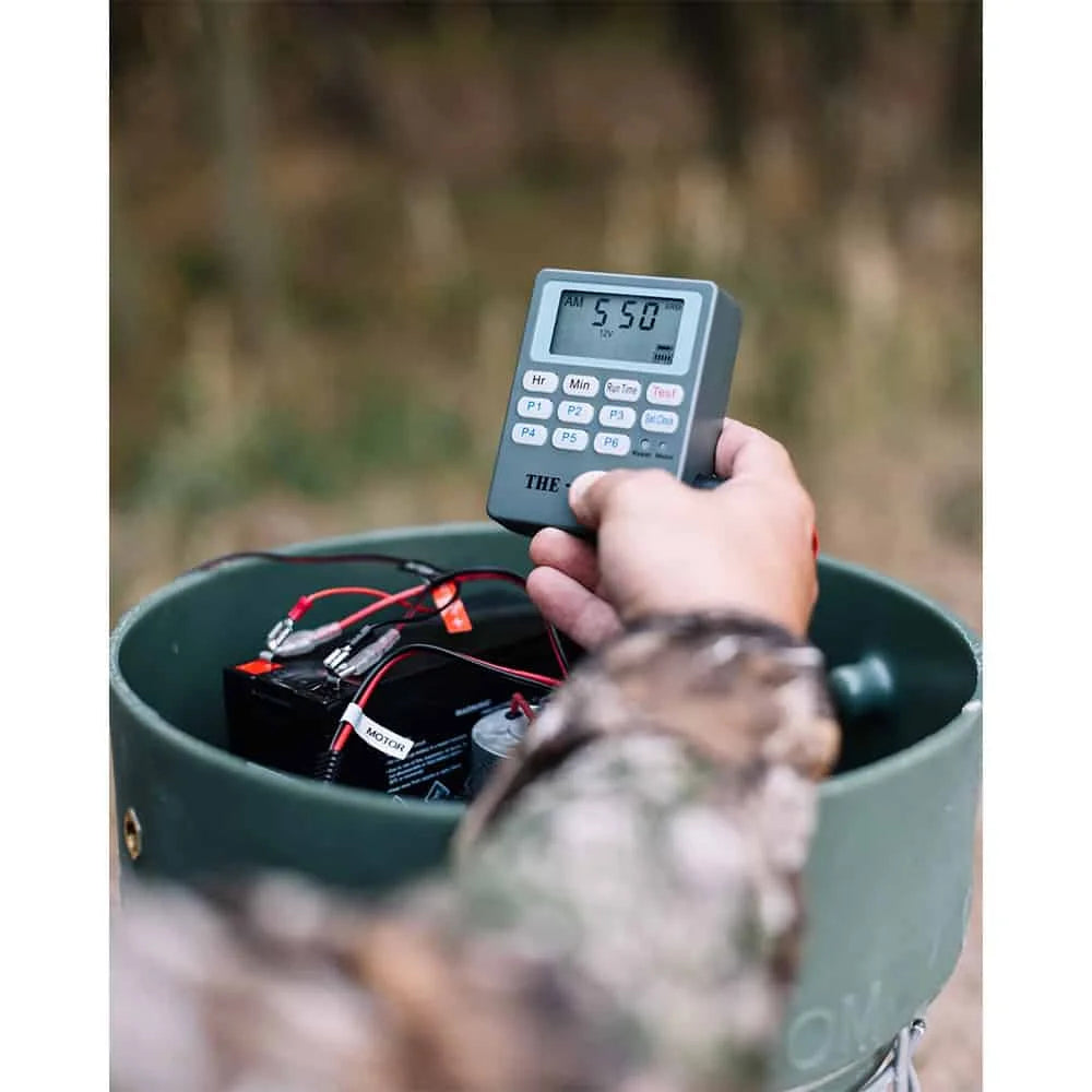 Capsule Feeders 200-LB Easy-Fill Game Feeder, hunter in camo programming digital timer controller over open feeder base