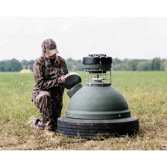 Capsule Feeders 250-LB Easy-Fill Game Feeder, hunter kneeling in field opening side access port cover on dome