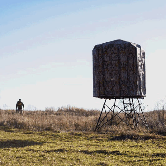 Muddy 360 tower hunting blind side view in grassy field