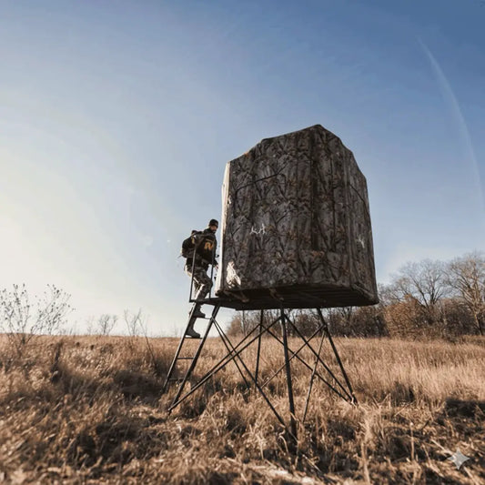 Muddy 360 elevated hunting blind rear angled view in dry grass terrain