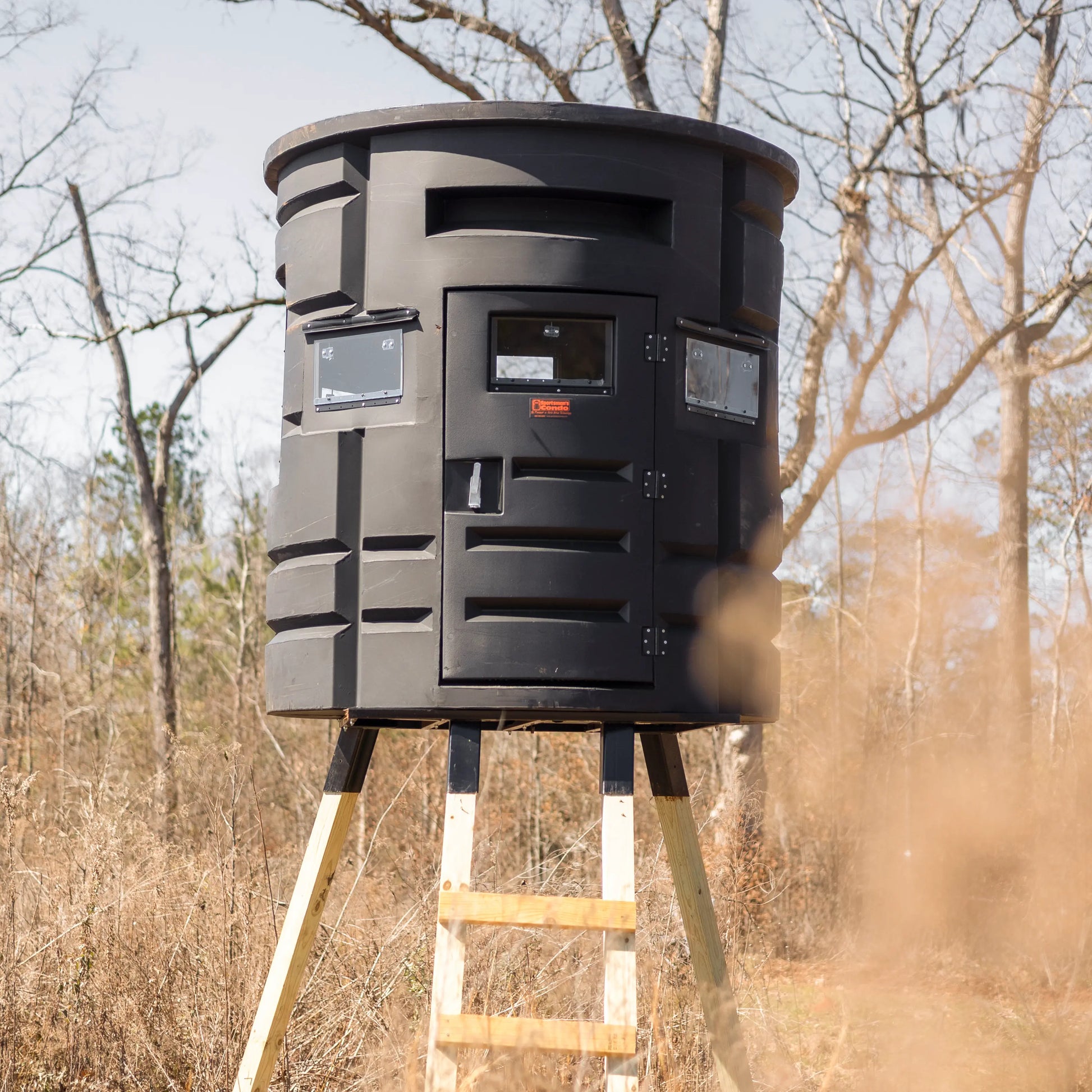 Angled front view of Sportsman Bow Condo elevated deer blind showing ladder and entry door