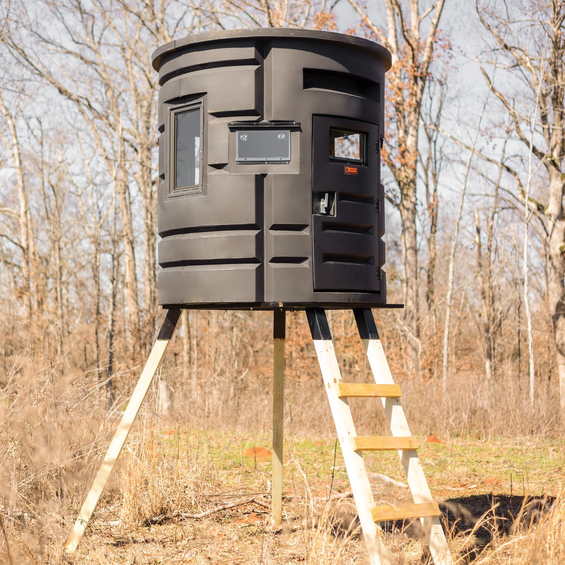 Front angle of Sportsman Bow Condo deer blind elevated on wooden platform in forested area