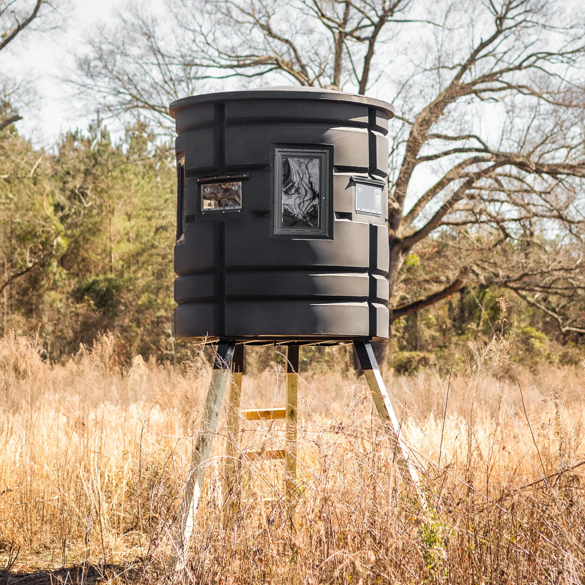 Front view of Sportsman Bow Condo elevated deer blind in grassy field with wooded background