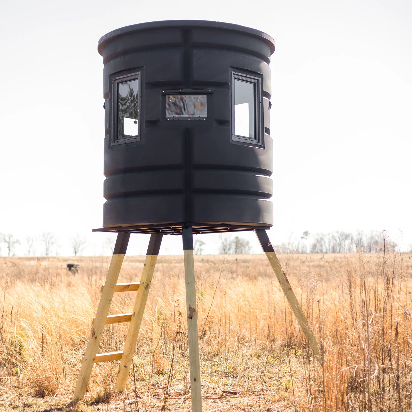 Side profile of Sportsman Bow Condo elevated deer blind with windows and ladder in an open grassy field