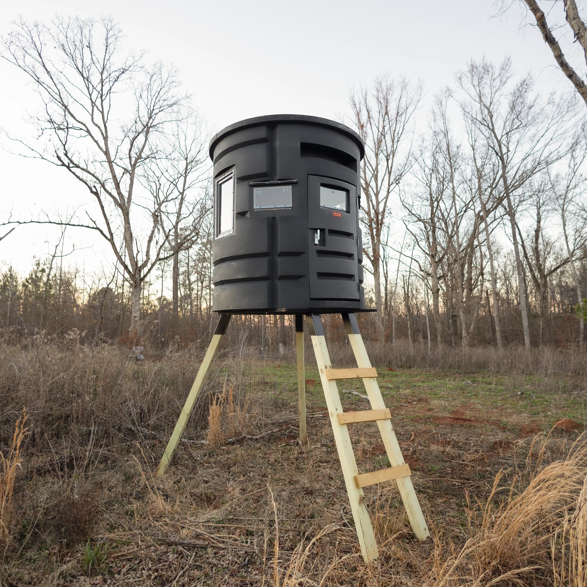 Sportsman Bow Condo elevated deer hunting blind with ladder setup in a wooded clearing