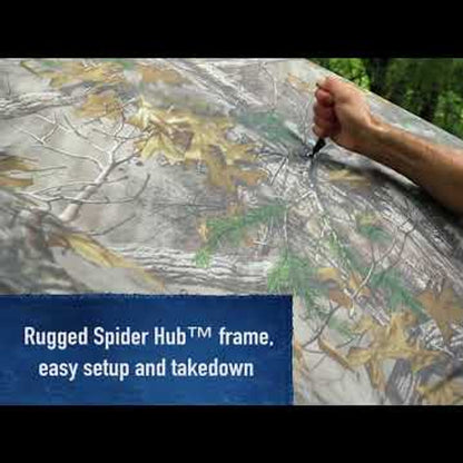 Ameristep Care Taker 55x55 pop-up ground blind showing hand operating Rugged Spider Hub frame for easy setup and takedown, Mossy Oak camouflage