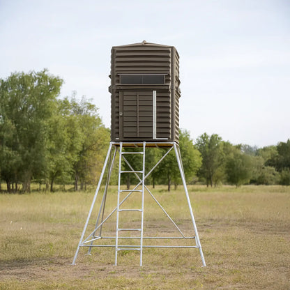 The Blynd 4x4 Deer Hunting Blind elevated on tall steel stand in an open grassy field, providing excellent visibility for rifle or crossbow hunting.

