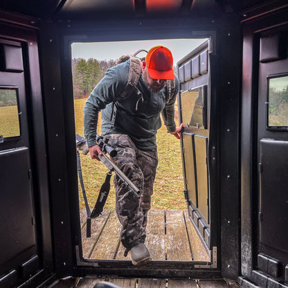 Hunter entering a Booner 6-Panel deer hunting blind through the door, interior perspective showing easy access and spacious design sold by Outdoors For Less