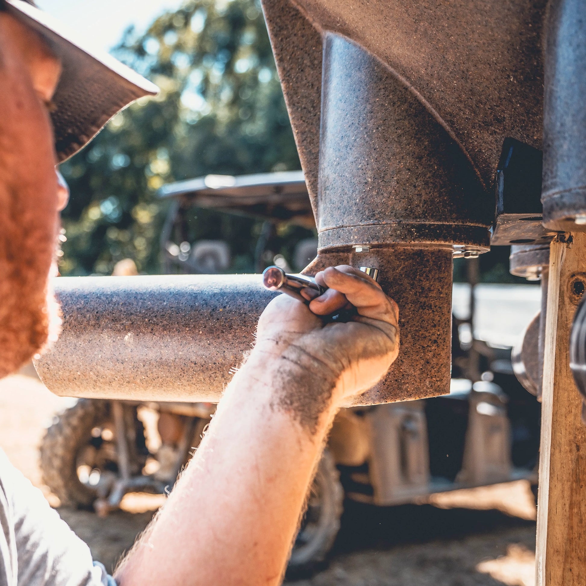 Boss Buck 200lb Post-Mounted Deer Feeder in workshop assembly — close-up view of brown rotomolded hopper attached to post sleeve, built for consistent deer feeding.