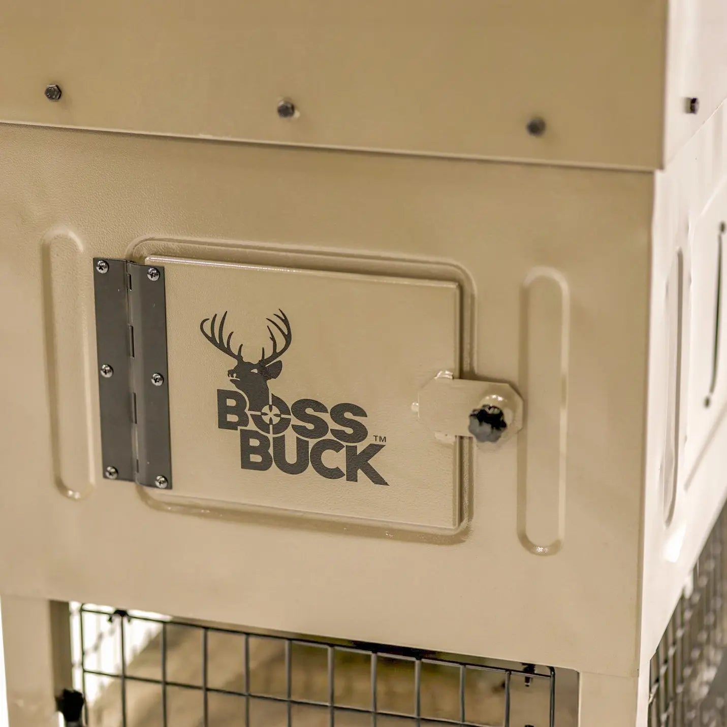 Close-up of Boss Buck 300lb Stand & Fill Automatic Sled Deer Feeder body — tan UV-resistant rotomolded construction with Boss Buck logo and secure latch door.