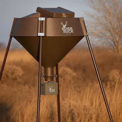 Boss Buck 600 lb Automatic Deer Feeder set up in field — brown rotomolded hopper on tripod stand with 12-volt timer and spinner system for consistent deer feeding.