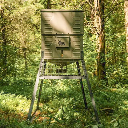 Boss Buck 600lb Stand & Fill Automatic Sled Deer Feeder set up in wooded field — tan rotomolded plastic feeder with 12-volt timer and easy top-fill lid for efficient deer feeding.