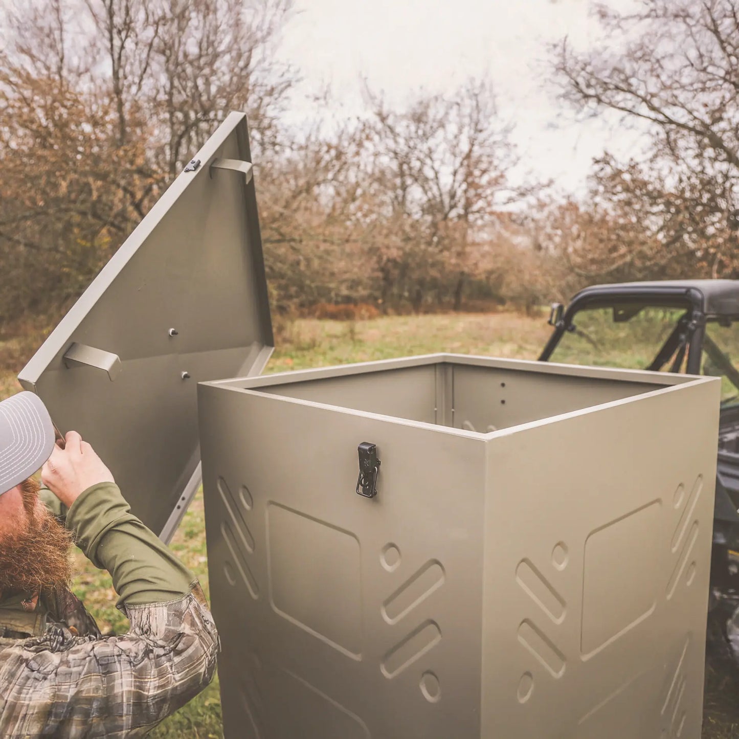 Boss Buck 600lb Stand & Fill Automatic Sled Deer Feeder being filled outdoors — large tan gravity hopper on skid base for easy transport and refill during hunting season.