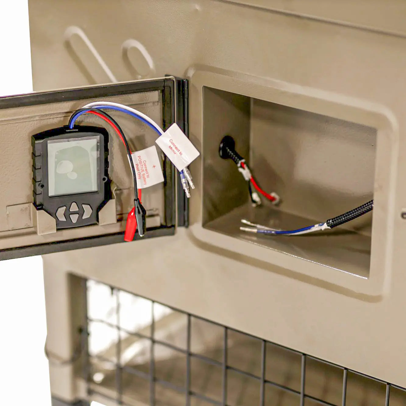 Close-up of Boss Buck 600lb Stand & Fill Automatic Sled Deer Feeder control box — internal 12-volt digital timer, spinner plate, and weather-protected electronics for precise feed distribution.