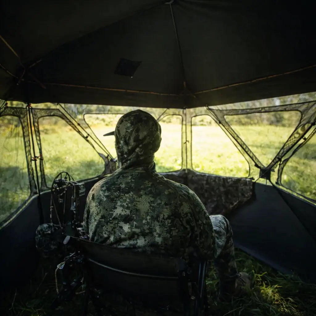 Hunter seated inside Muddy Epic Camo Infinity ground hunting blind with shooting windows open