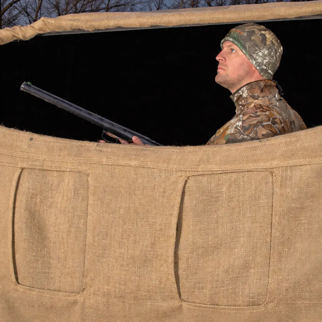 Hunter sitting inside Muddy Bale Blind concealed in tall grass