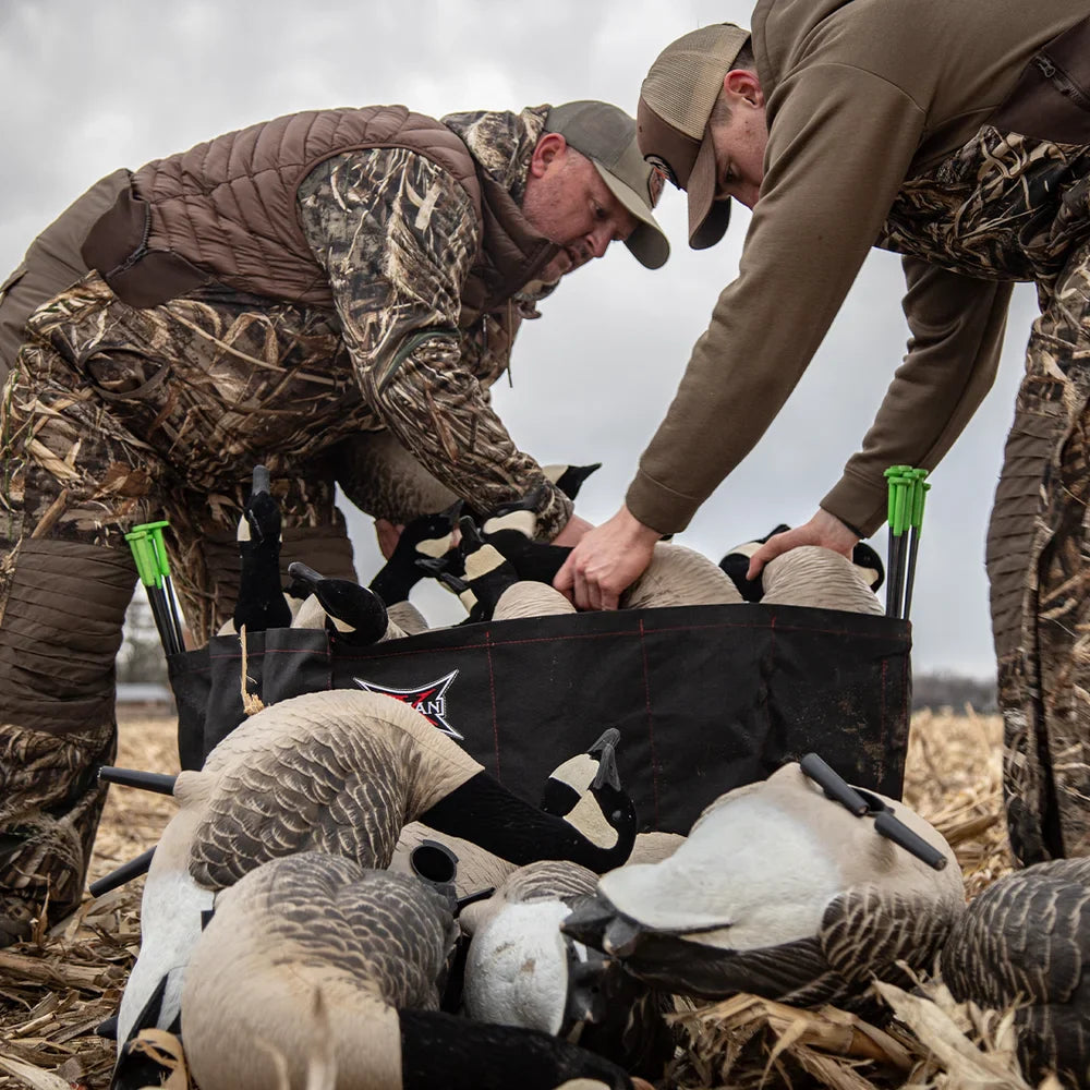 Two hunters packing Avian-X AXP Honkers decoys into branded bag in cornfield