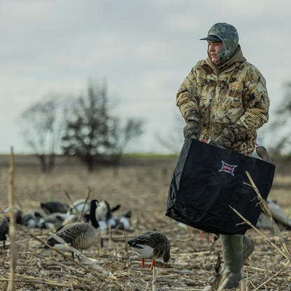 Hunter with Avian-X decoy bag standing in goose decoy spread in harvested field