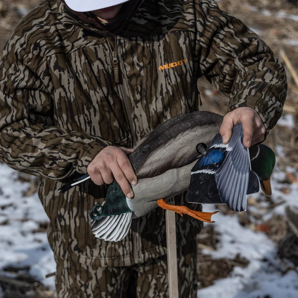 Hunter in Mossy Oak camo assembling wings on Avian-X Powerflight Mallard decoy in the field