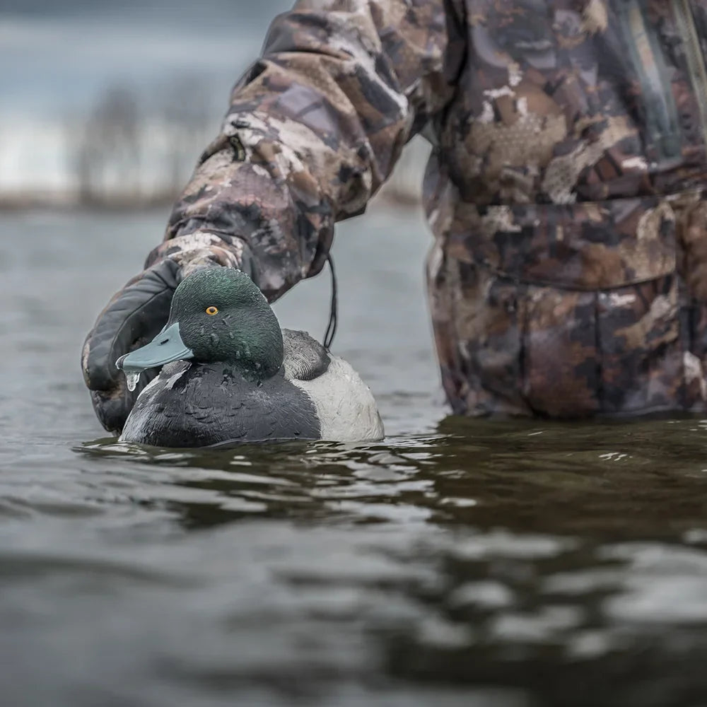 Close-up of Avian-X TopFlight Bluebills drake decoy on water held by hunter in camo glove