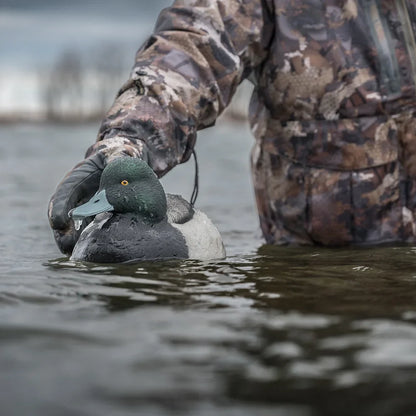 Close-up of Avian-X TopFlight Bluebills drake decoy on water held by hunter in camo glove