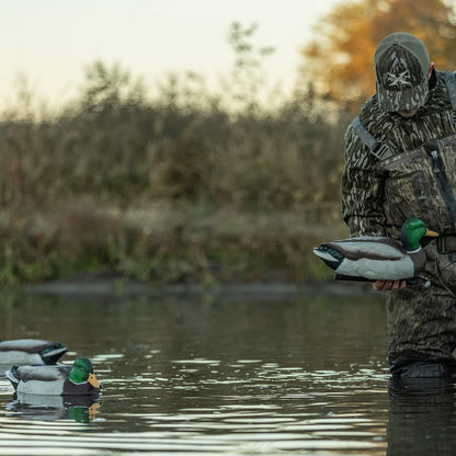 Hunter in Avian-X camo placing TopFlight Mallard decoys on pond at sunset