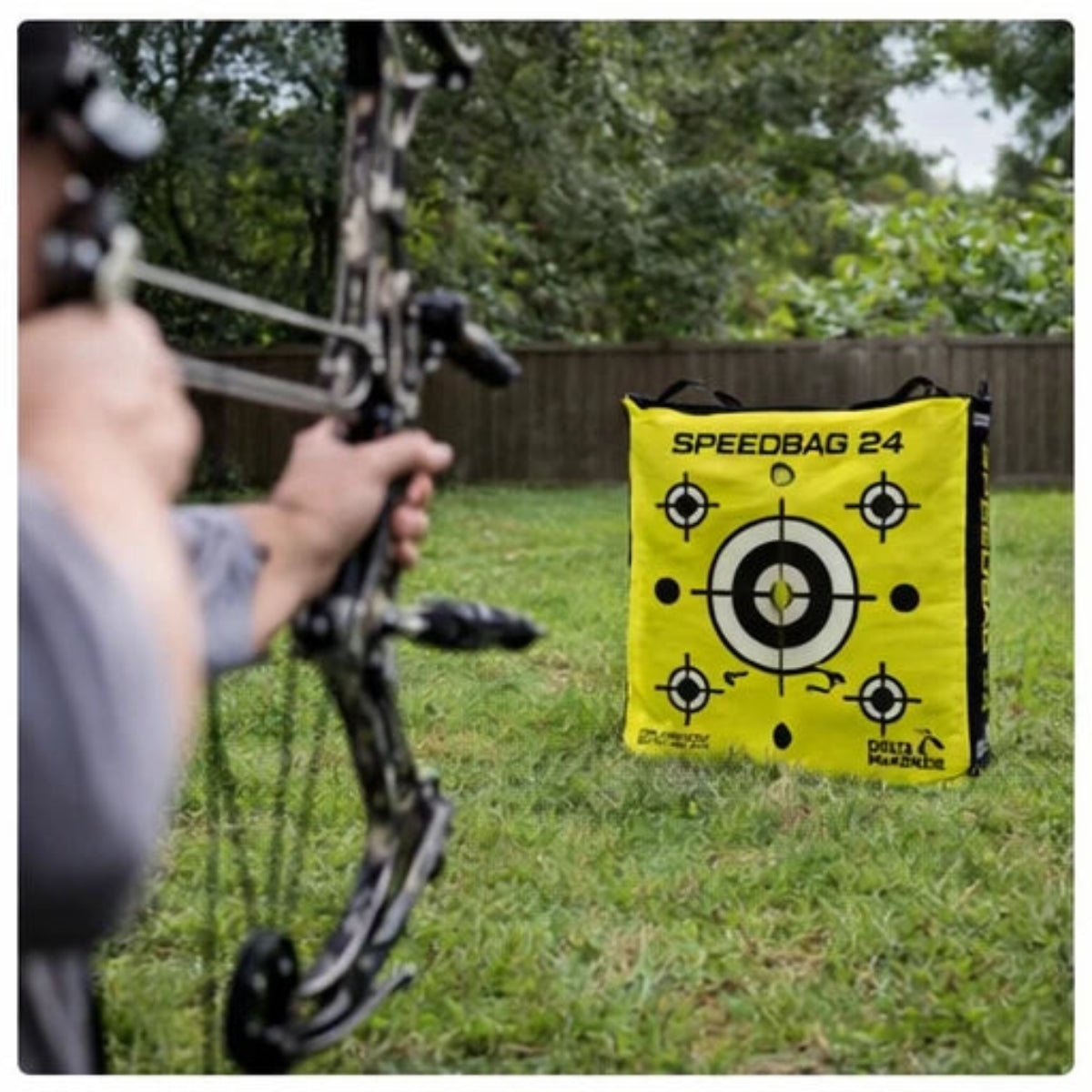 Archer with a bow and arrow aiming at a Delta McKenzie'Speedbag 24' in an outdoor setting.
