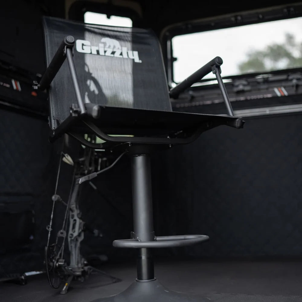 Grizzly Alpha Swivel Blind Chair installed inside a hunting blind, side angle showing seat and pedestal