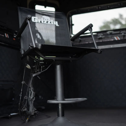 Grizzly Alpha Swivel Blind Chair installed inside a hunting blind, side angle showing seat and pedestal