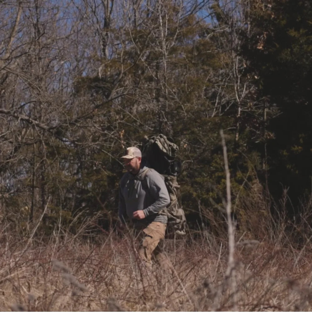Horn Hunter Blind Hog Pack lifestyle shot, hunter carrying loaded pack while walking through brushy woodland terrain