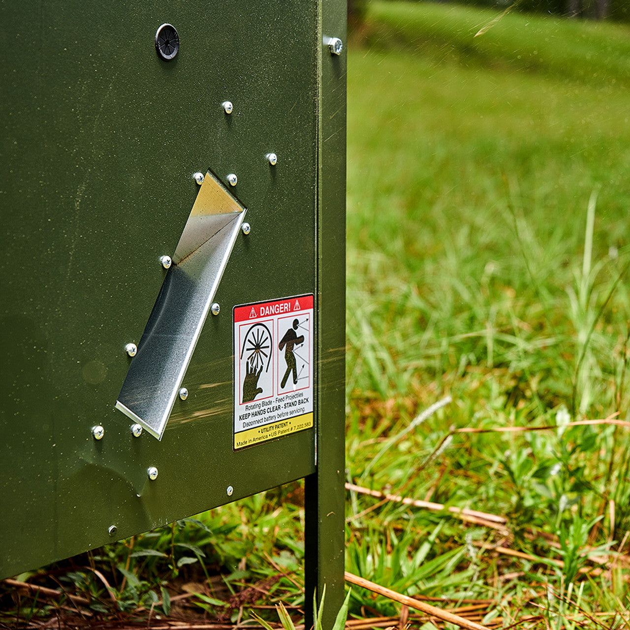 Close-up of the angled feed dispenser chute on a Texas Hunter feeder, showing the feed being thrown 
