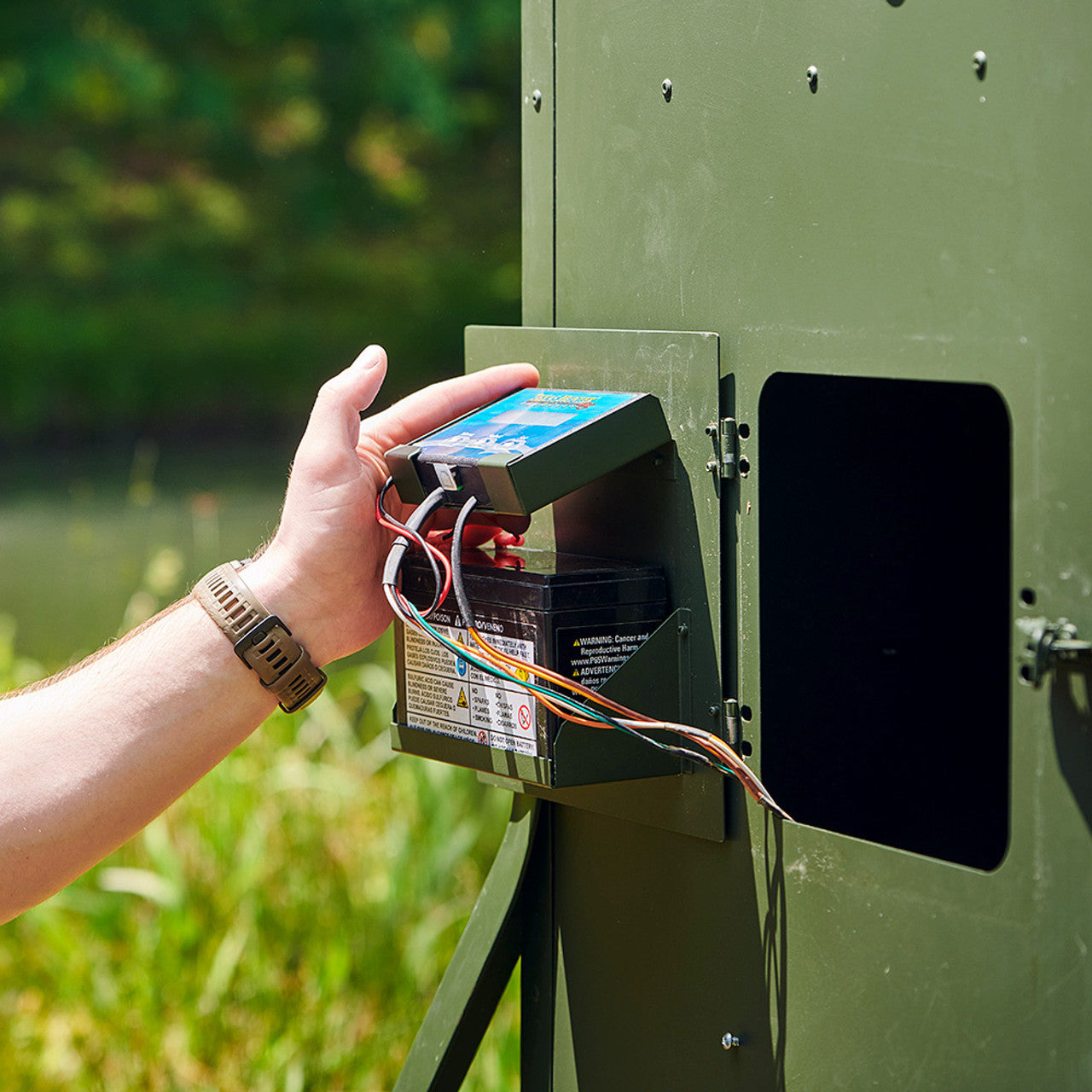 Man removing the Texas Hunter digital timer and battery unit from inside the feeder
