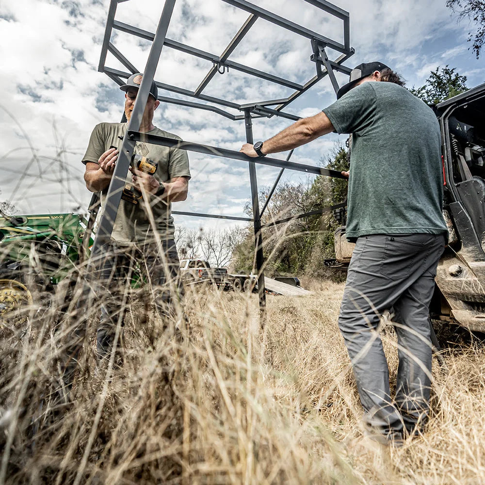 Two men assembling Titan Hunting Blinds 8 ft. tower frame in field next to UTV