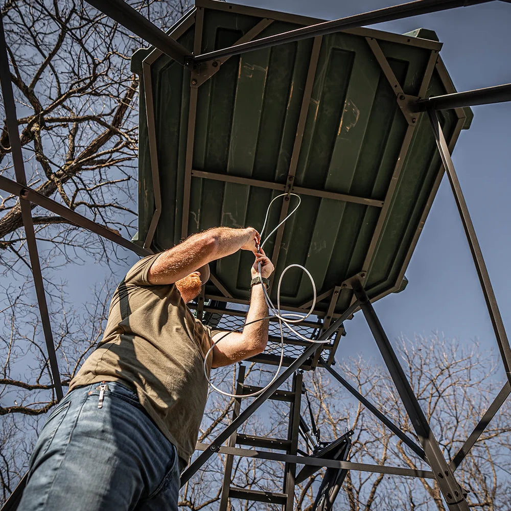 Man installing wiring on roof of Titan blind atop 8 ft. tower with porch and ladder