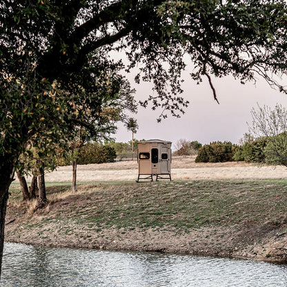 Titan Hunting Blinds Blind Base Skid with blind set up in a field beside a pond