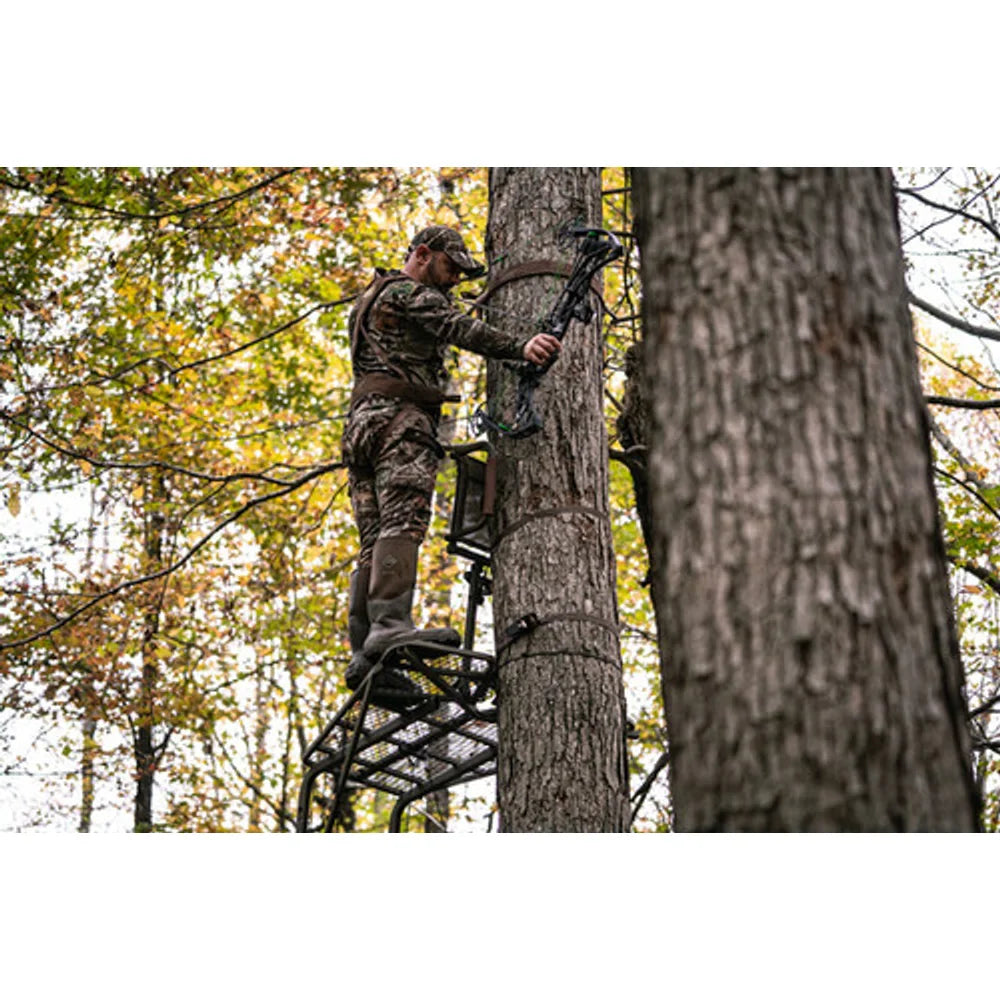 Hunter in camo climbing Trophy Treestands Freedom ladder stand with compound bow in fall woods