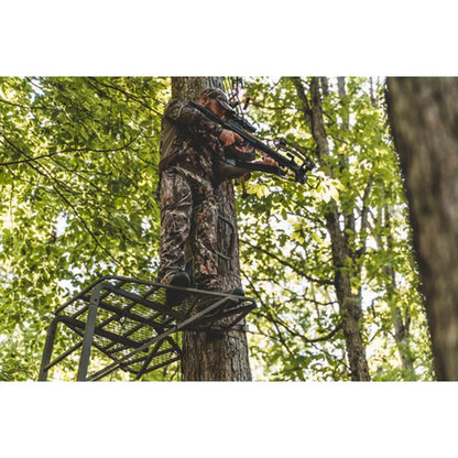 Hunter aiming crossbow from Trophy Treestands Freedom ladder stand platform in green woods