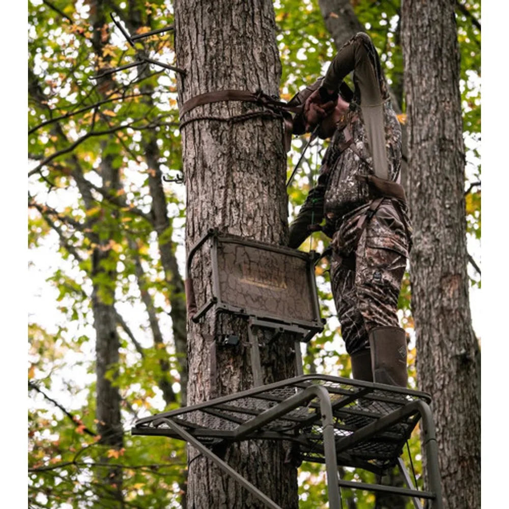 Hunter attaching safety strap on Trophy Treestands Freedom ladder stand in autumn woods