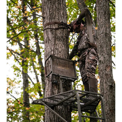 Hunter attaching safety strap on Trophy Treestands Freedom ladder stand in autumn woods