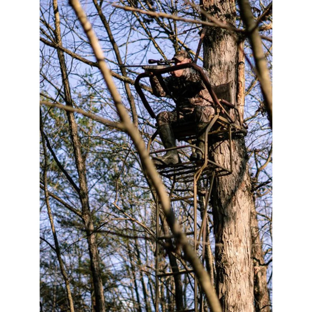Hunter aiming rifle from Trophy Treestands Gunny ladder stand in bare-branch woods