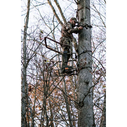 Hunter using Trophy Treestands Strike Eagle ladder stand in tree aiming a crossbow during hunt